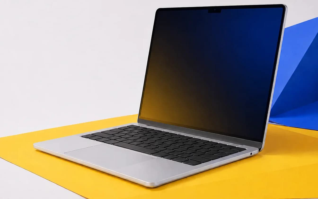 Laptop terbuka di atas alas kertas kuning dengan latar terang.